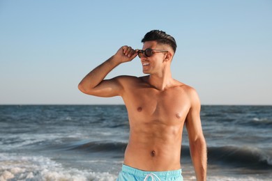 Photo of Handsome man with attractive body on beach