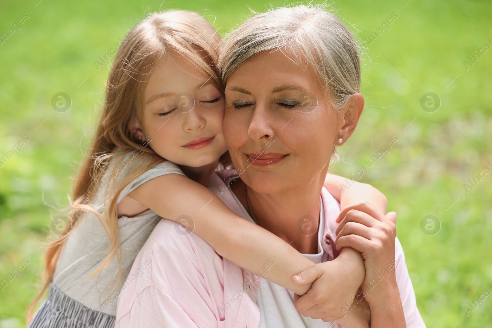 Photo of Happy grandmother hugging her granddaughter spending time together outdoors