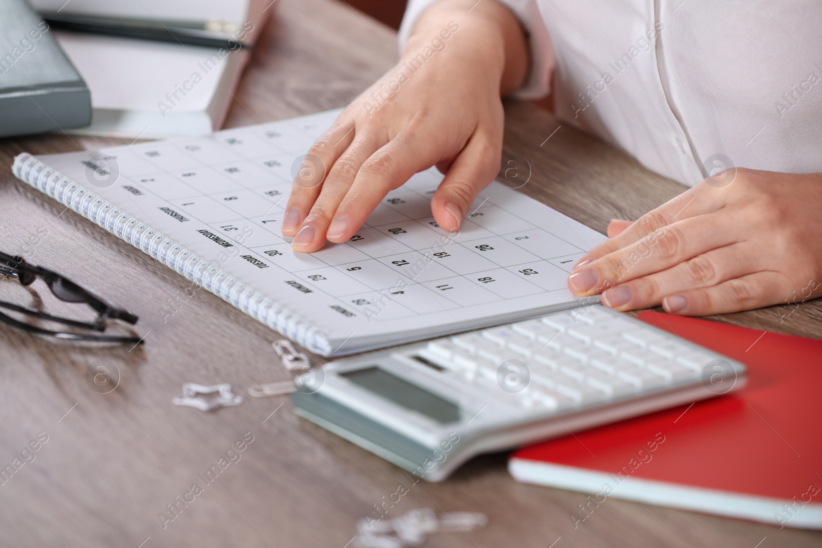 Photo of Woman with calendar at wooden table, closeup