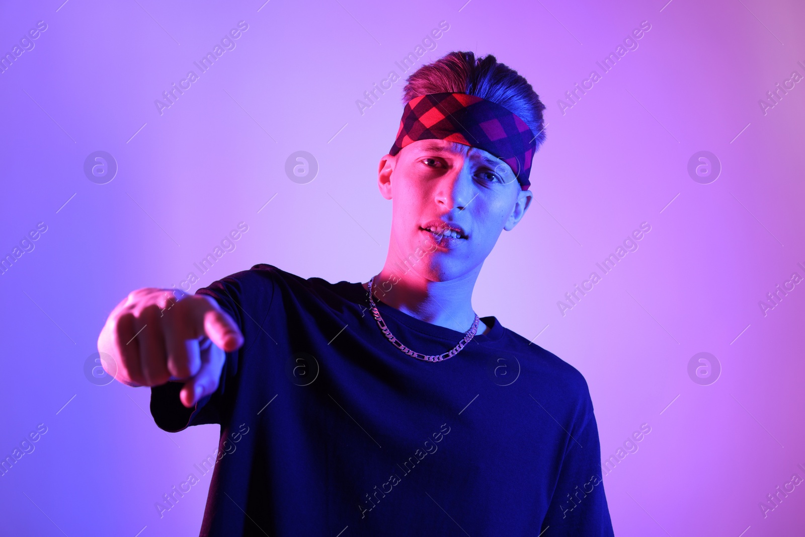 Photo of Stylish young man on color background in neon lights