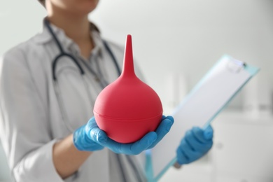 Photo of Doctor holding pink enema in hospital, closeup