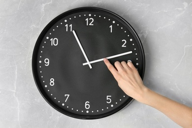 Photo of Woman changing time on big wall clock