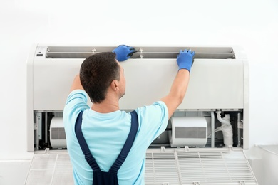 Technician installing and checking air conditioner indoors