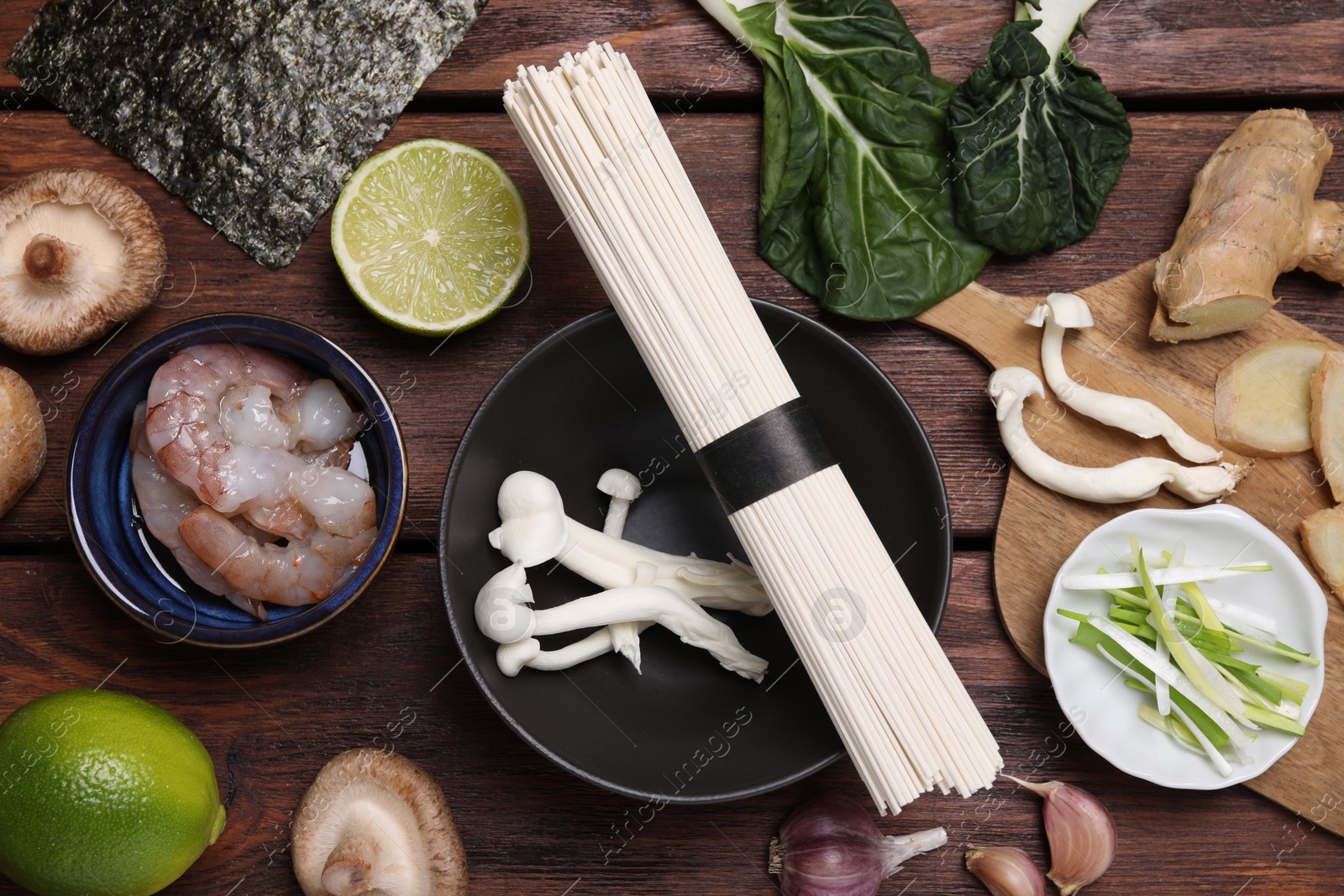 Photo of Cooking delicious ramen soup. Different ingredients on wooden table, flat lay