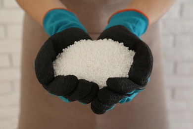 Woman holding pile of granular mineral fertilizer on blurred background, closeup