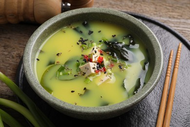 Photo of Bowl of delicious miso soup with tofu served on wooden table, closeup
