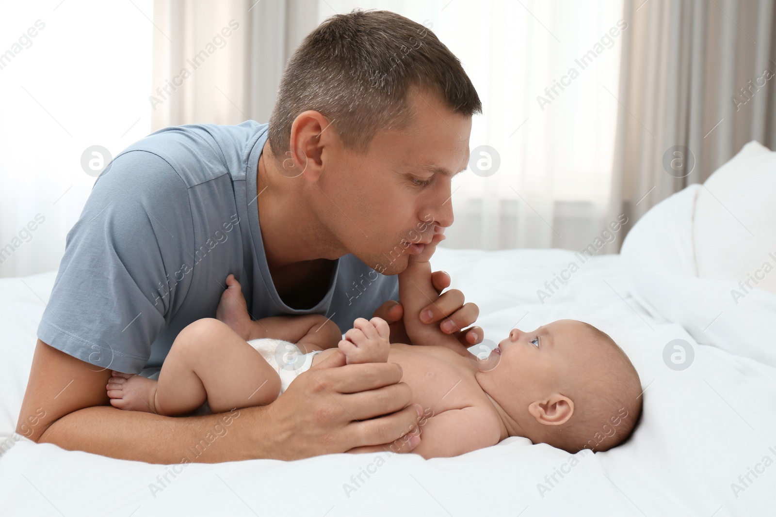 Photo of Father with his cute baby on bed at home