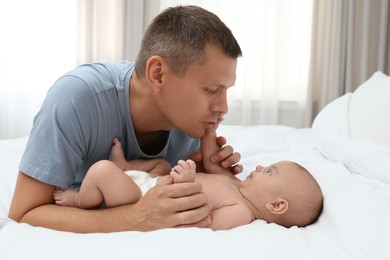 Photo of Father with his cute baby on bed at home