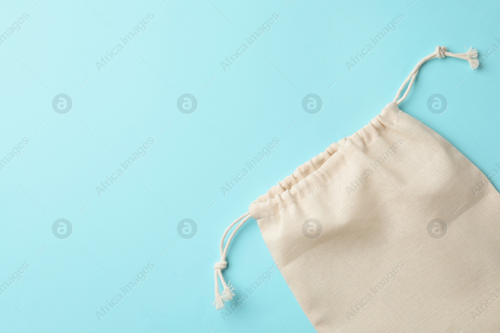 Photo of Cotton eco bag on light blue background, top view. Space for text