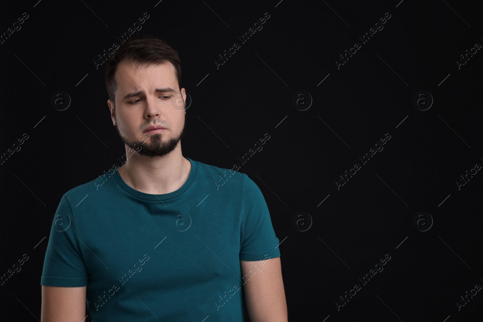 Photo of Portrait of sad man on black background, space for text