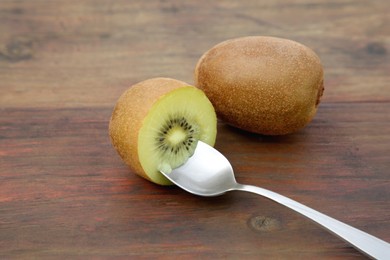 Photo of Fresh ripe yellow kiwis with spoon on wooden table