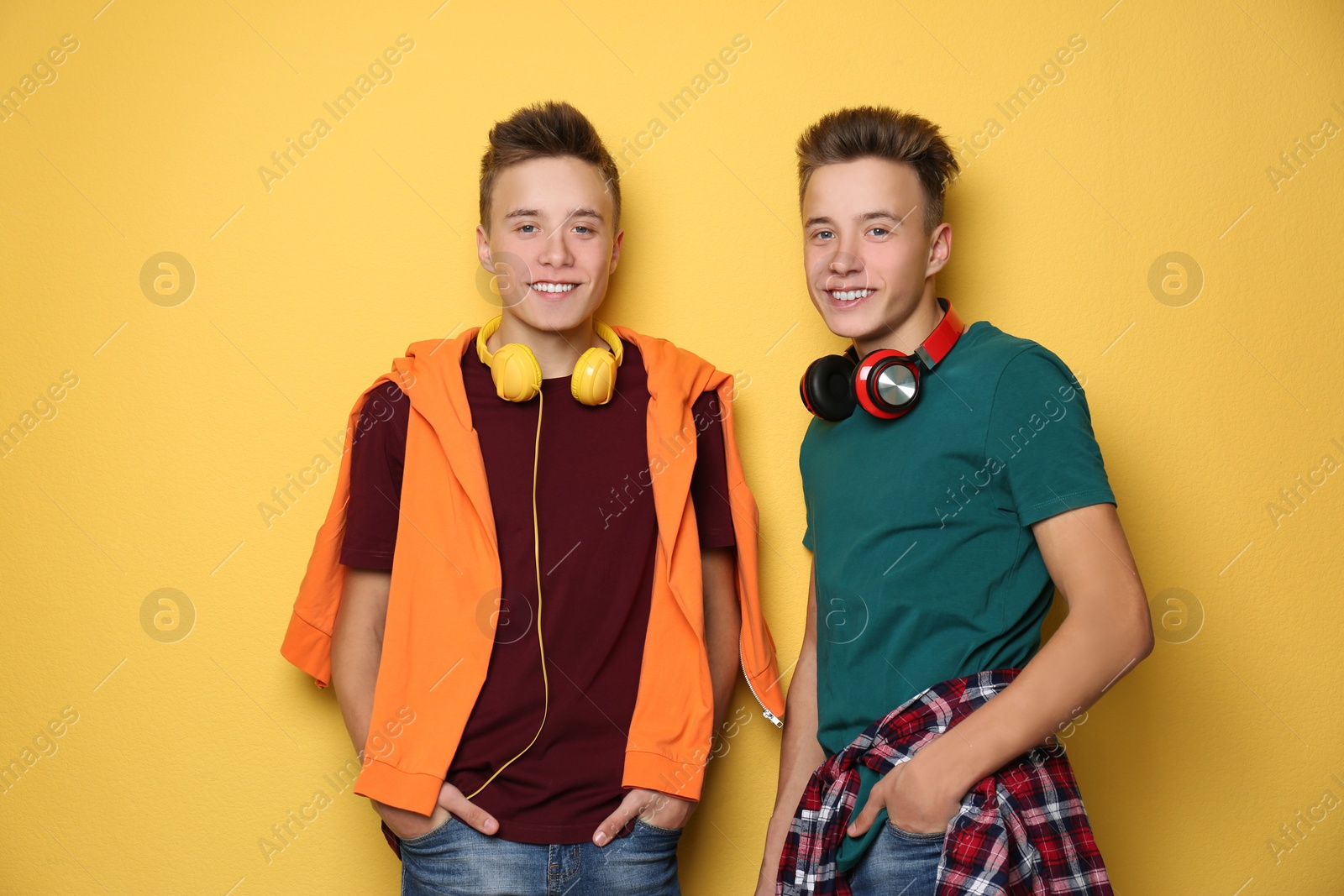 Photo of Teenage twin brothers with headphones on color background