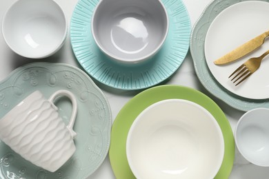 Beautiful ceramic dishware, cup and cutlery on white table, flat lay