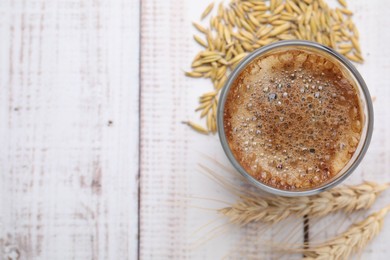 Photo of Cup of barley coffee, grains and spikes on white wooden table, flat lay. Space for text