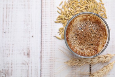 Cup of barley coffee, grains and spikes on white wooden table, flat lay. Space for text