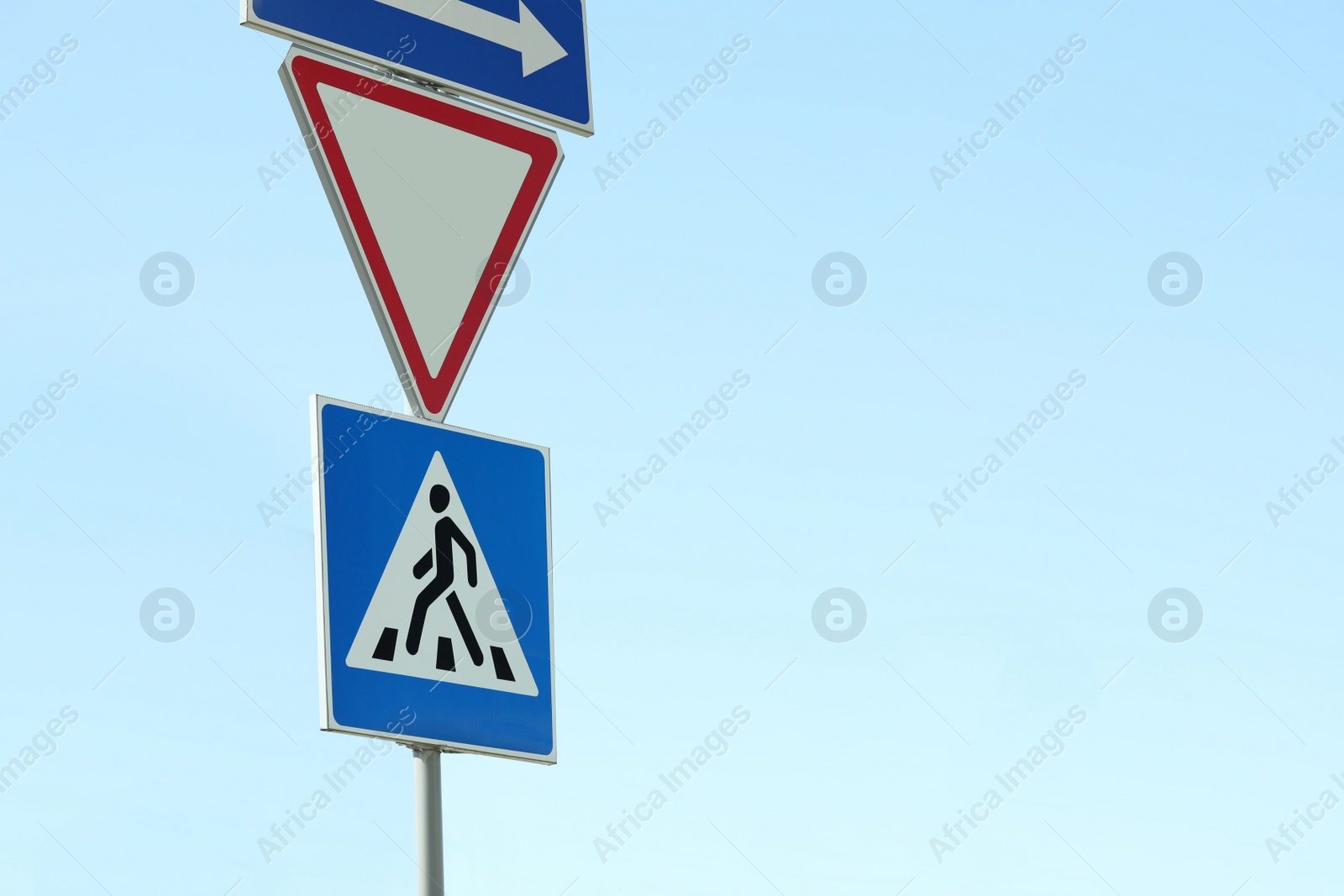 Photo of Post with Pedestrian Crossing and other traffic signs in city on sunny day