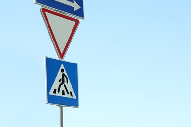 Post with Pedestrian Crossing and other traffic signs in city on sunny day