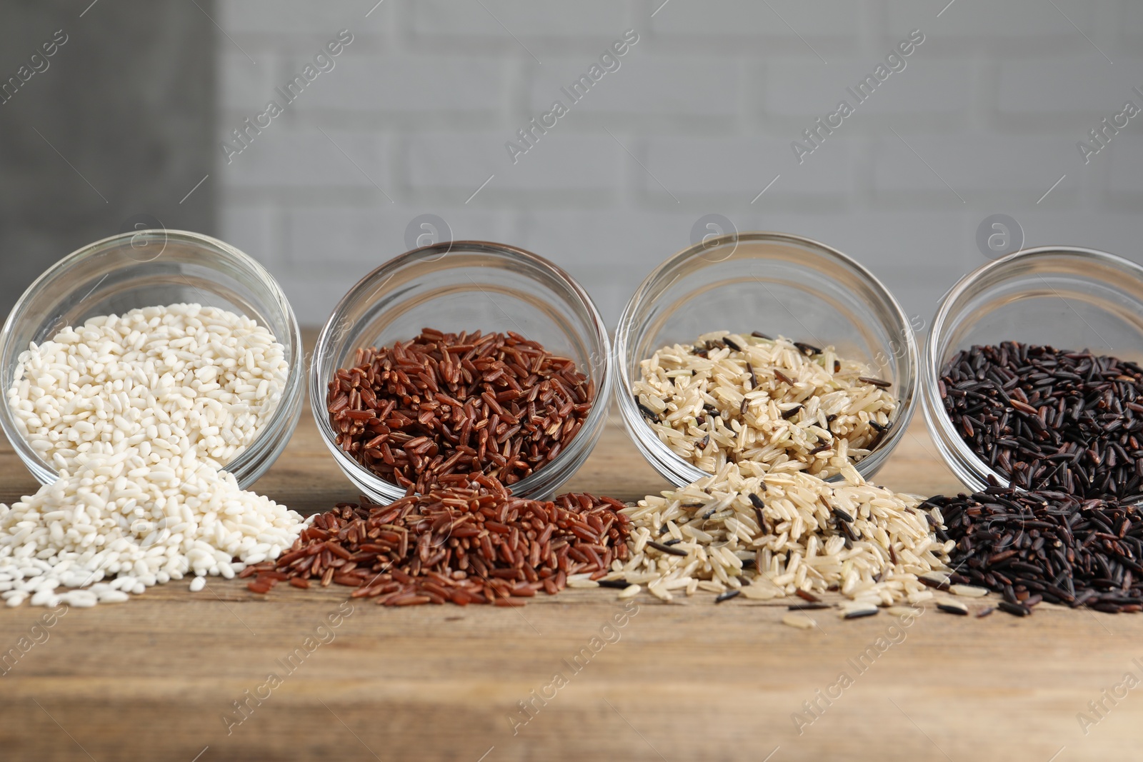 Photo of Different types of rice on wooden table, closeup