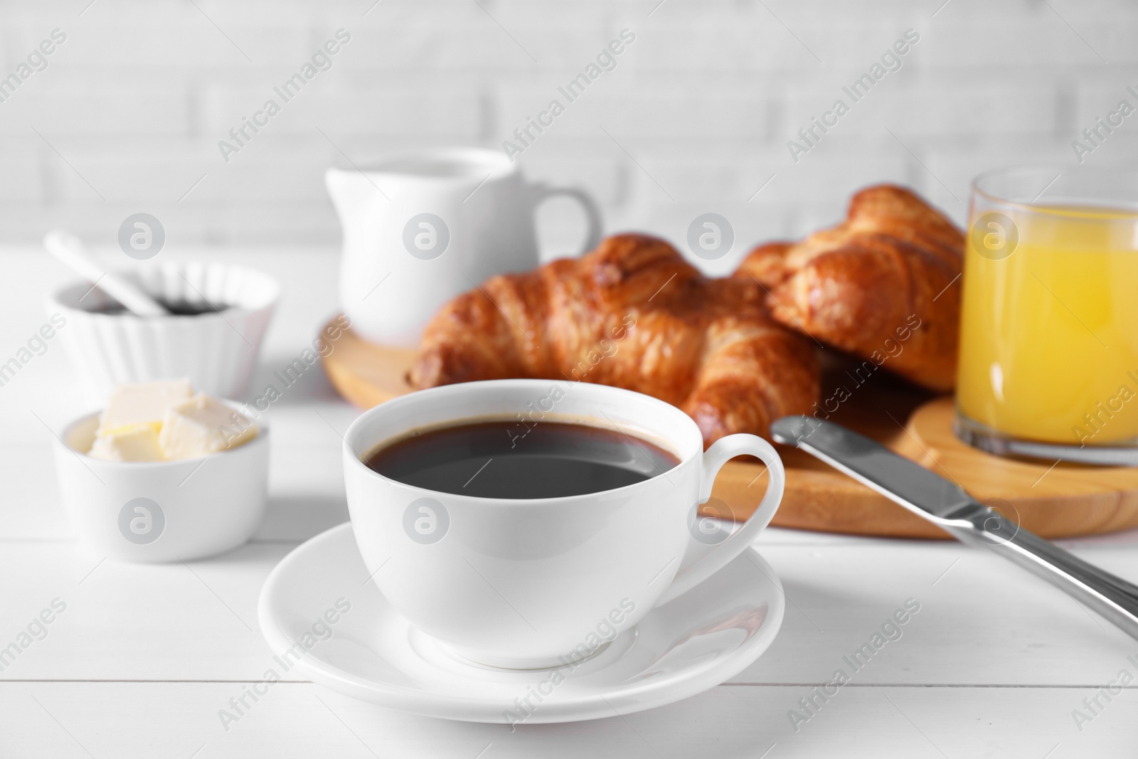 Photo of Fresh croissants, butter and coffee on white wooden table. Tasty breakfast