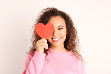 Photo of African-American woman with paper heart on white background