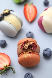 Delicious macarons and berries on light blue table, closeup