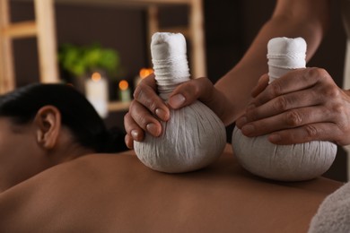 Young woman receiving herbal bag massage in spa salon, closeup