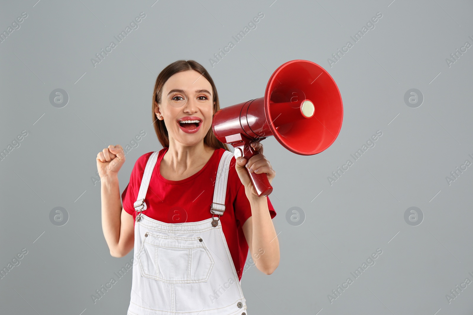 Photo of Emotional young woman with megaphone on light grey background