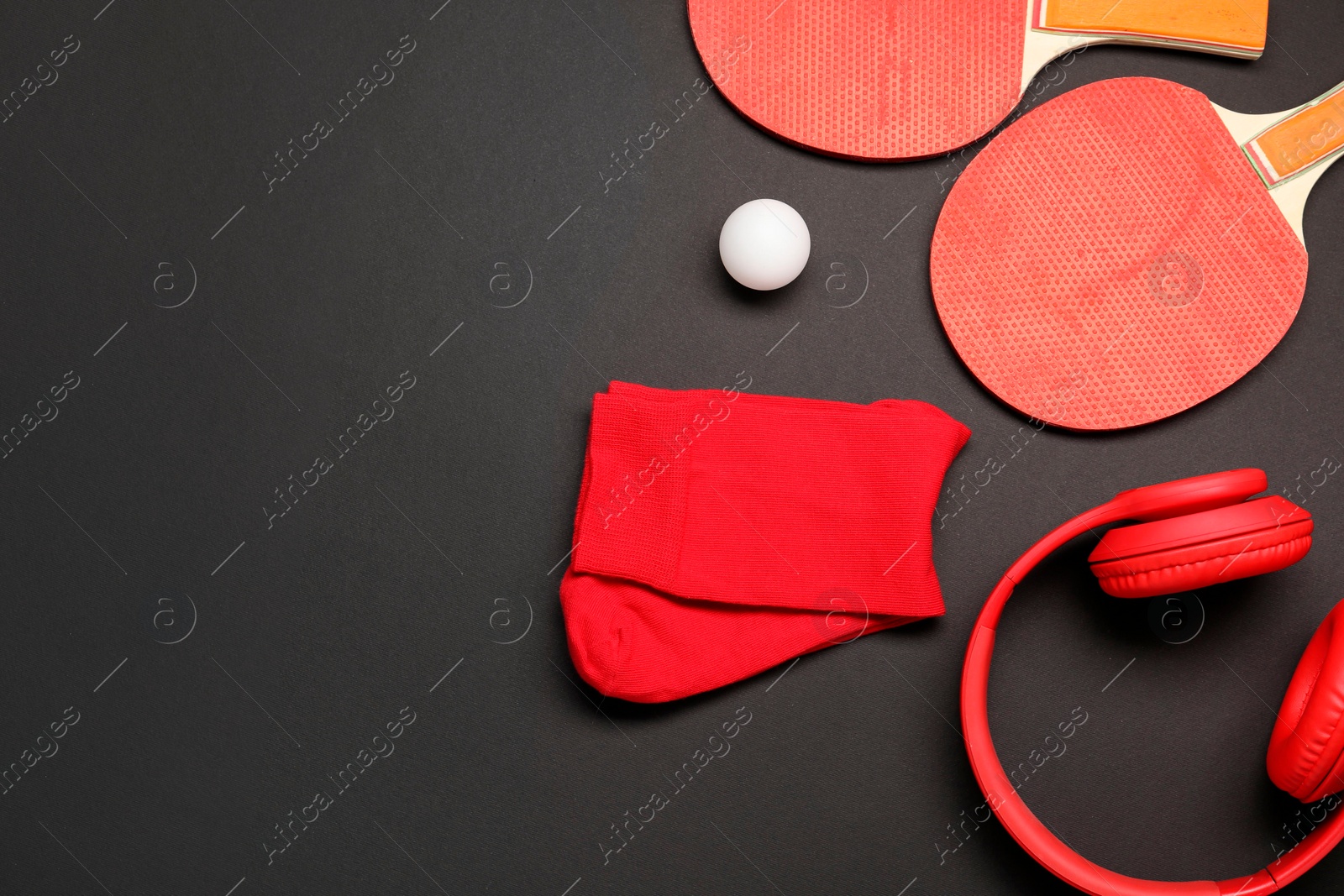 Photo of Sports equipment. Ping pong rackets, ball, headphones and socks on black background, flat lay. Space for text