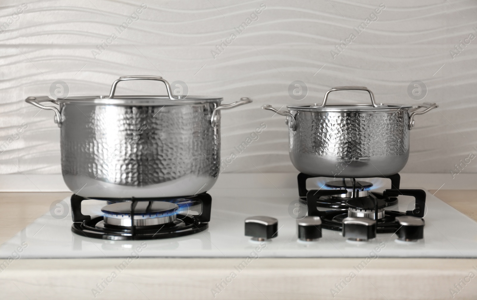 Photo of Shiny steel saucepans on modern gas stove