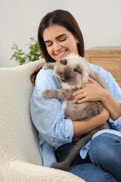 Photo of Woman with her cute cat on soft armchair at home