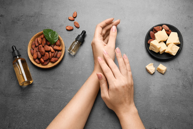 Woman applying organic cocoa butter at table, top view