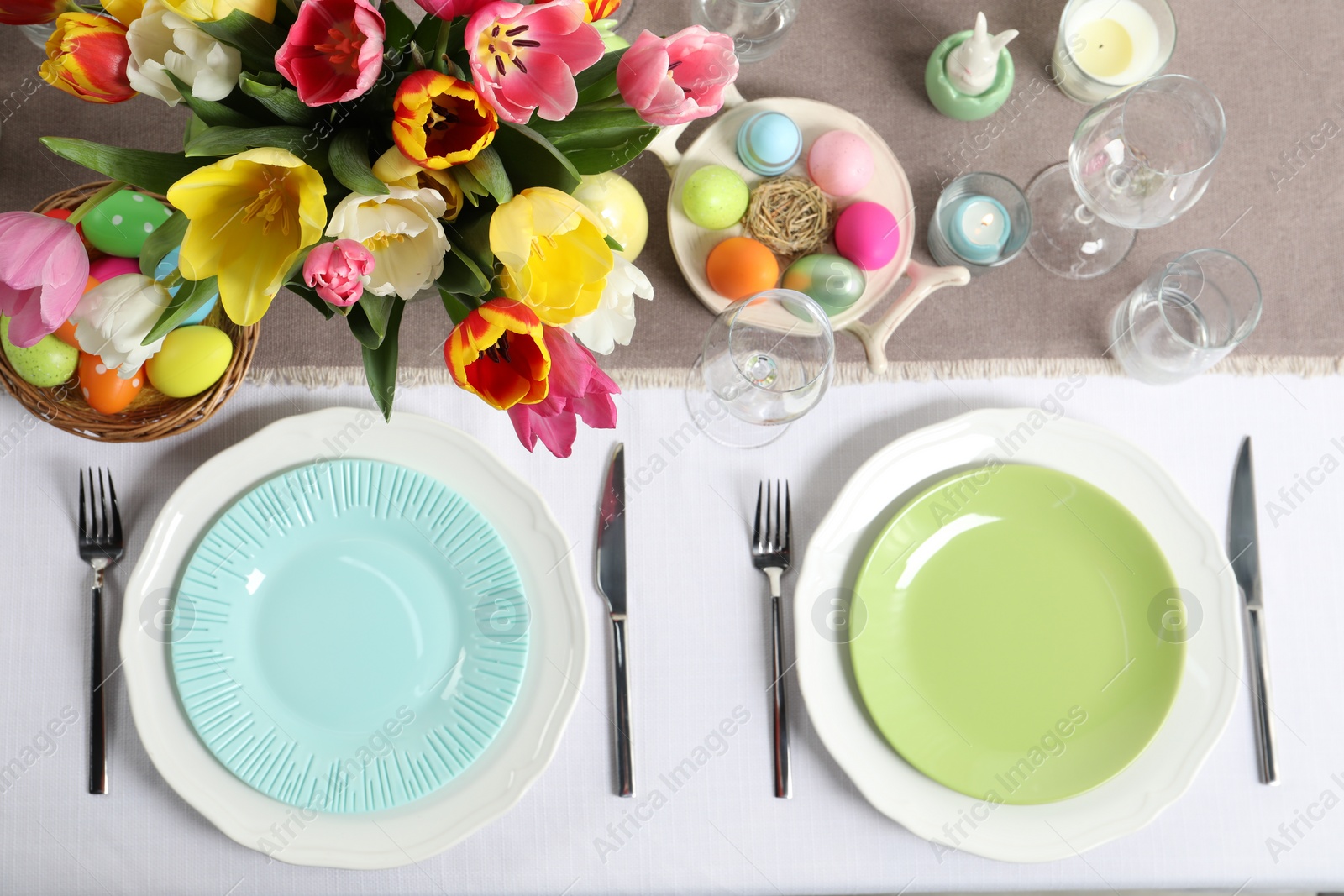 Photo of Easter celebration. Festive table setting with beautiful flowers and painted eggs, flat lay