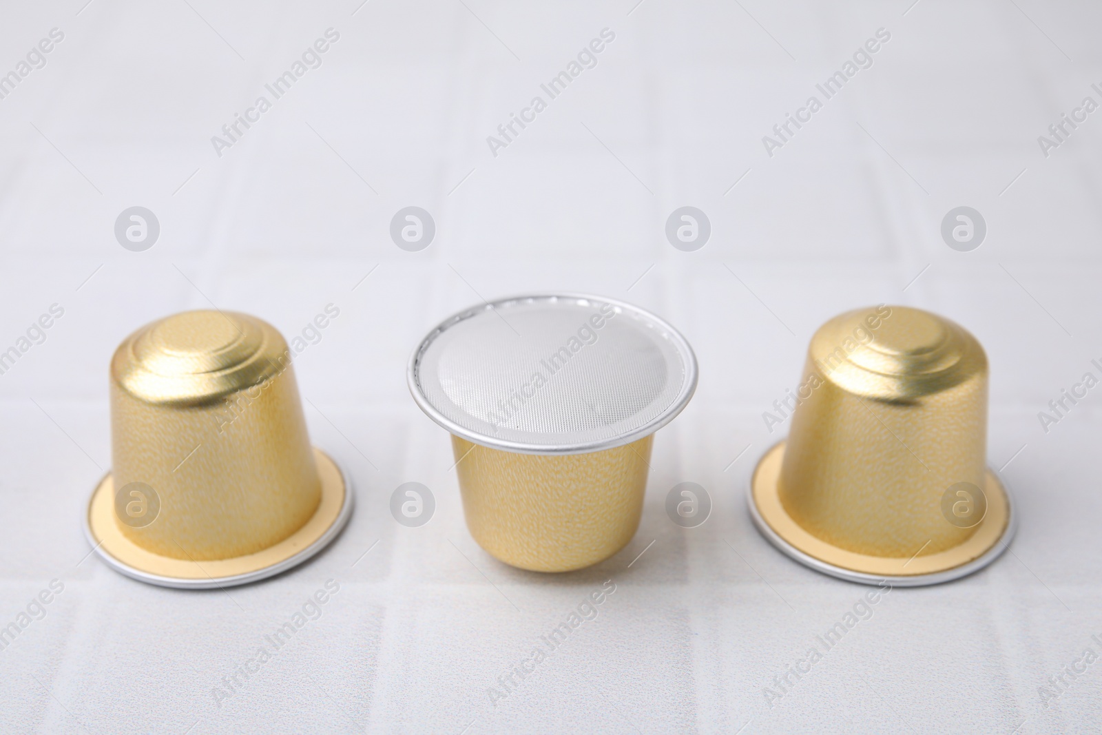 Photo of Coffee capsules on white tiled table, closeup