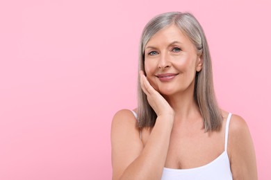 Portrait of beautiful senior woman on pink background. Space for text