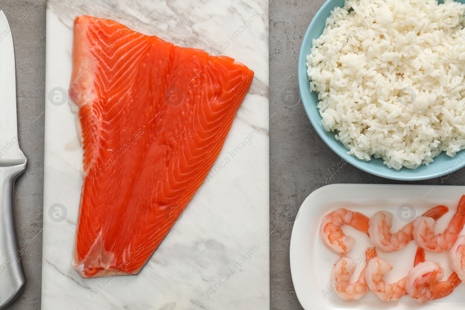 Photo of Fresh salmon, shrimps and rice for sushi on grey textured table, flat lay