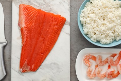 Photo of Fresh salmon, shrimps and rice for sushi on grey textured table, flat lay