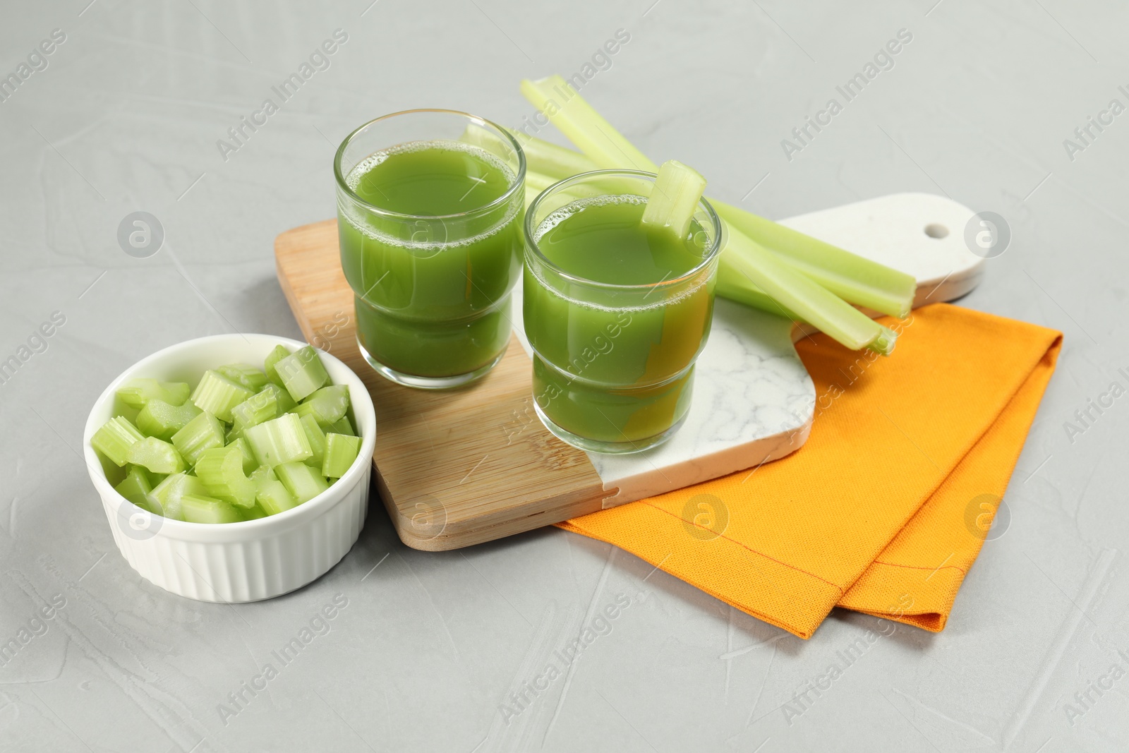Photo of Celery juice and fresh vegetables on light gray table