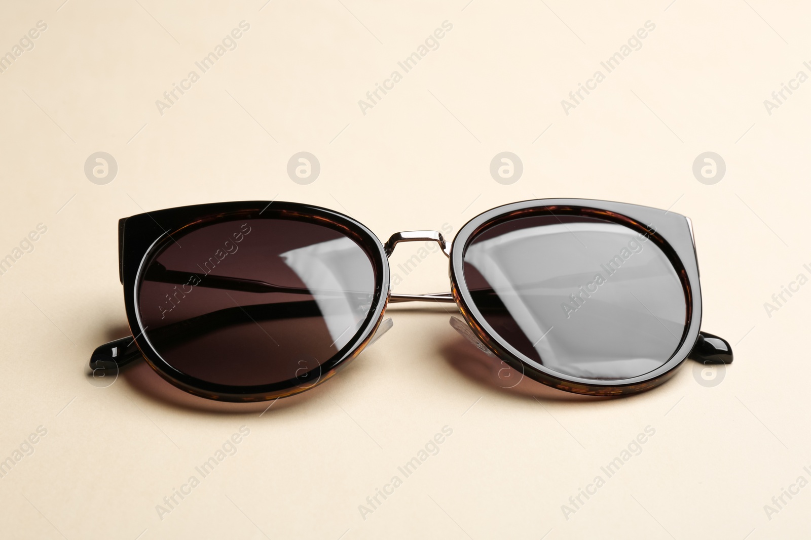 Photo of Stylish sunglasses on beige background. Fashionable accessory