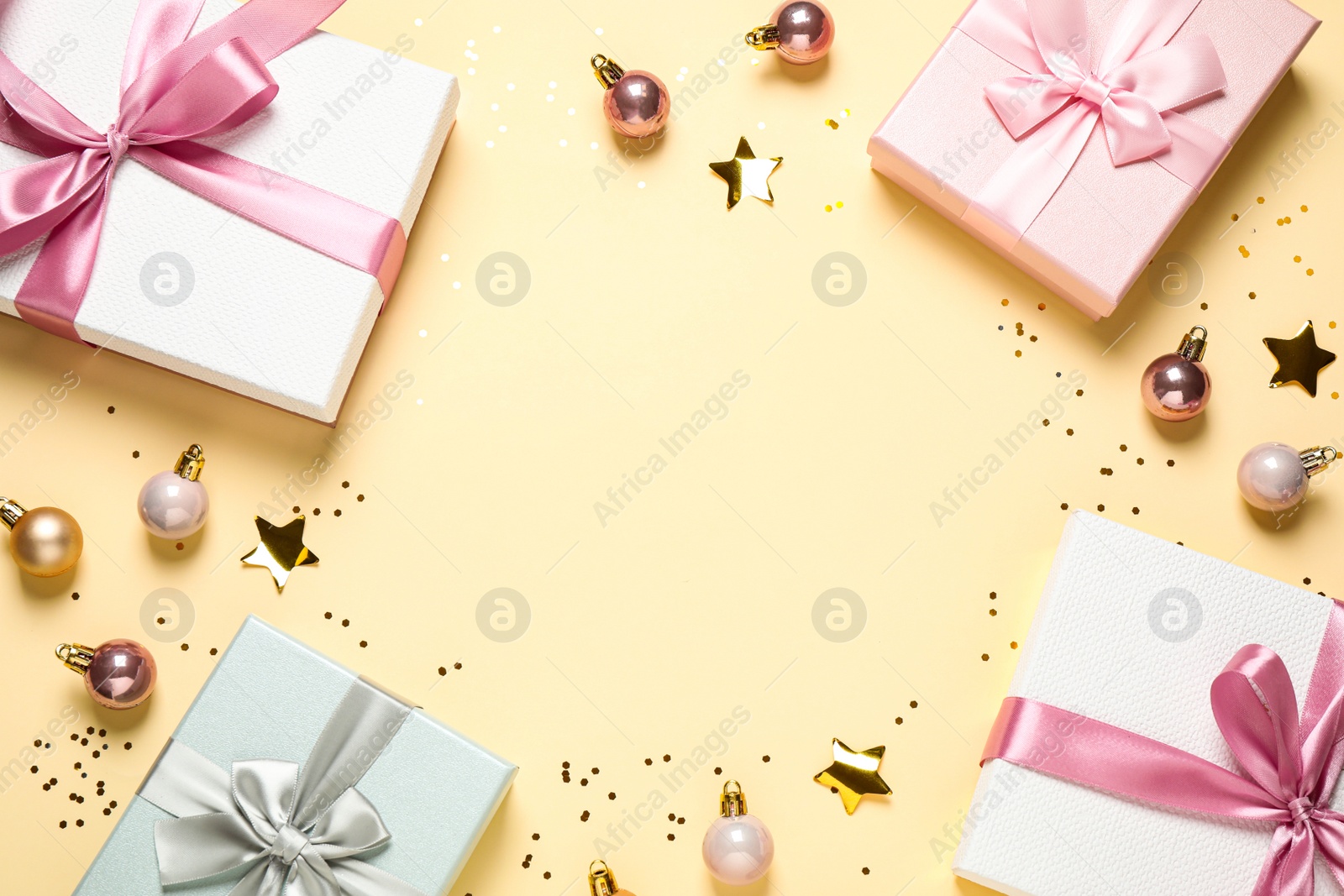 Photo of Frame of beautiful gift boxes and Christmas balls on beige background, flat lay. Space for text