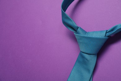Photo of One necktie on purple background, above view. Space for text
