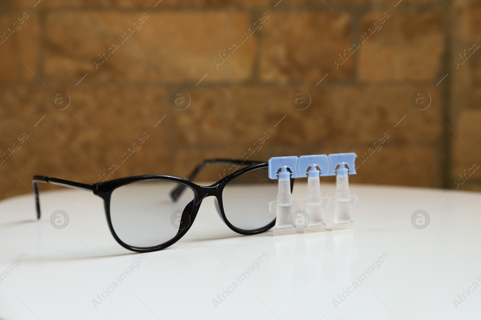 Photo of Single dose eye drops and glasses on white table