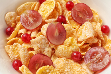 Photo of Corn flakes with berries in bowl, closeup. Healthy breakfast