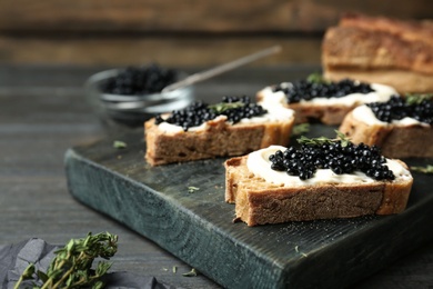 Sandwiches with black caviar and butter on wooden board