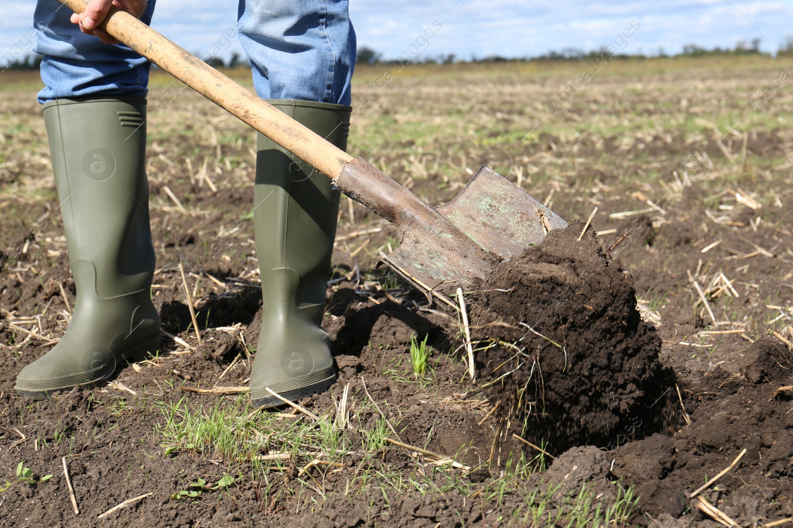 Photo of Man digging soil with shovel in field, closeup