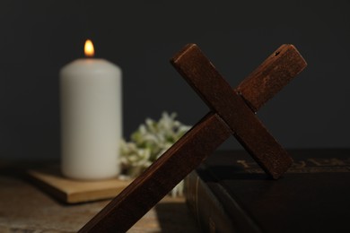 Photo of Cross, Bible, church candle and flowers on wooden table, space for text