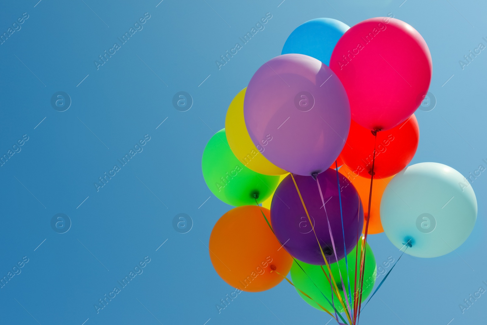 Photo of Bunch of colorful balloons against blue sky. Space for text