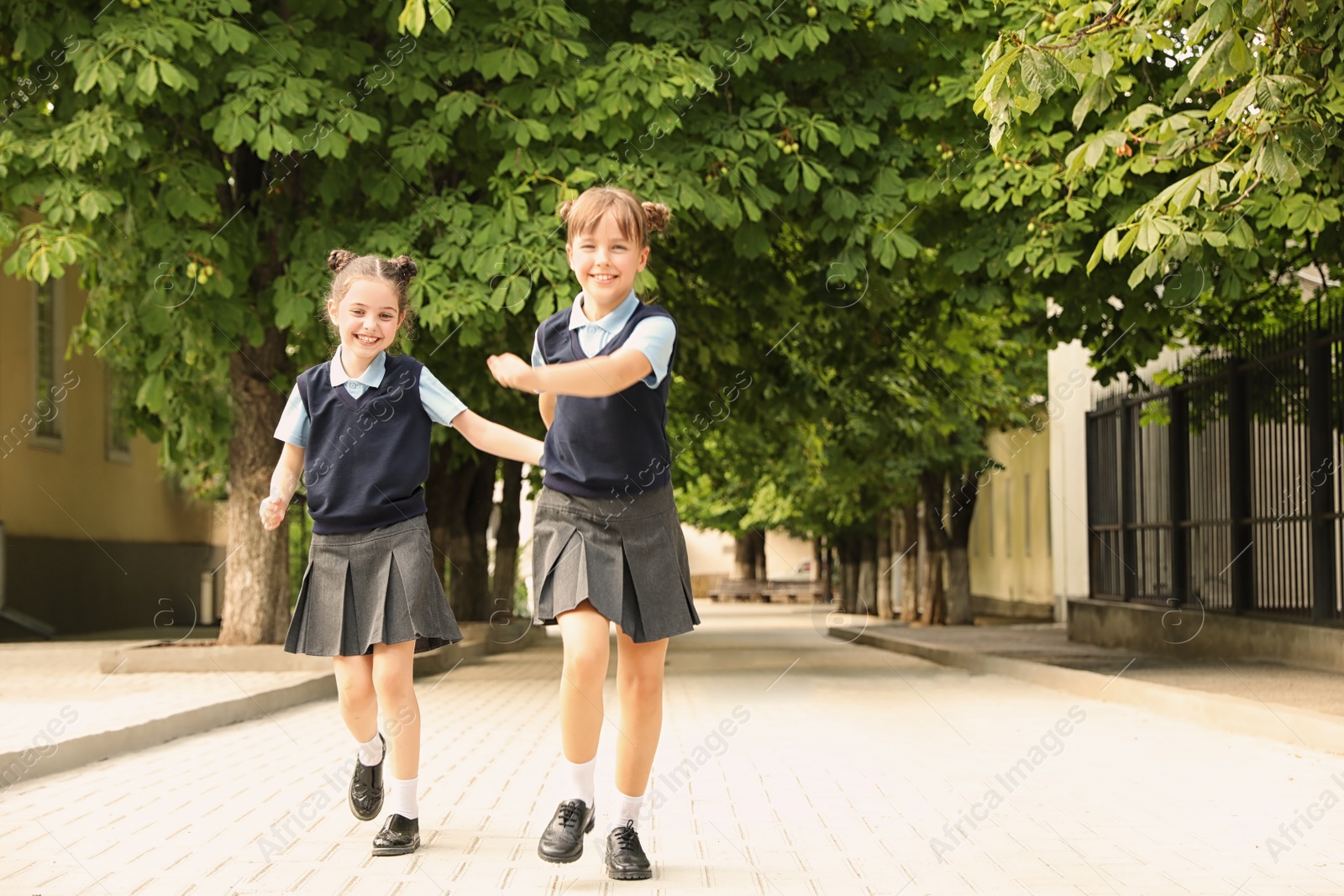 Photo of Little girls in stylish school uniform outdoors