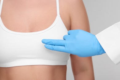 Photo of Mammologist checking woman's breast on light grey background, closeup