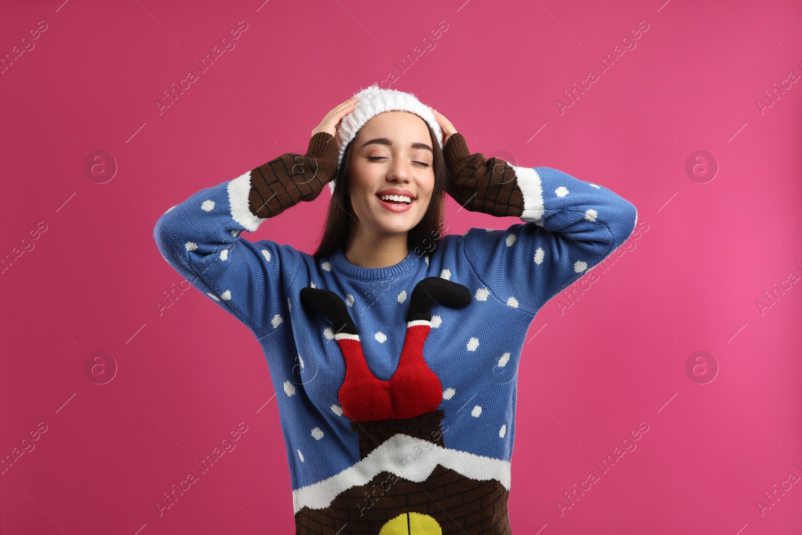 Photo of Young woman in Christmas sweater and hat on pink background