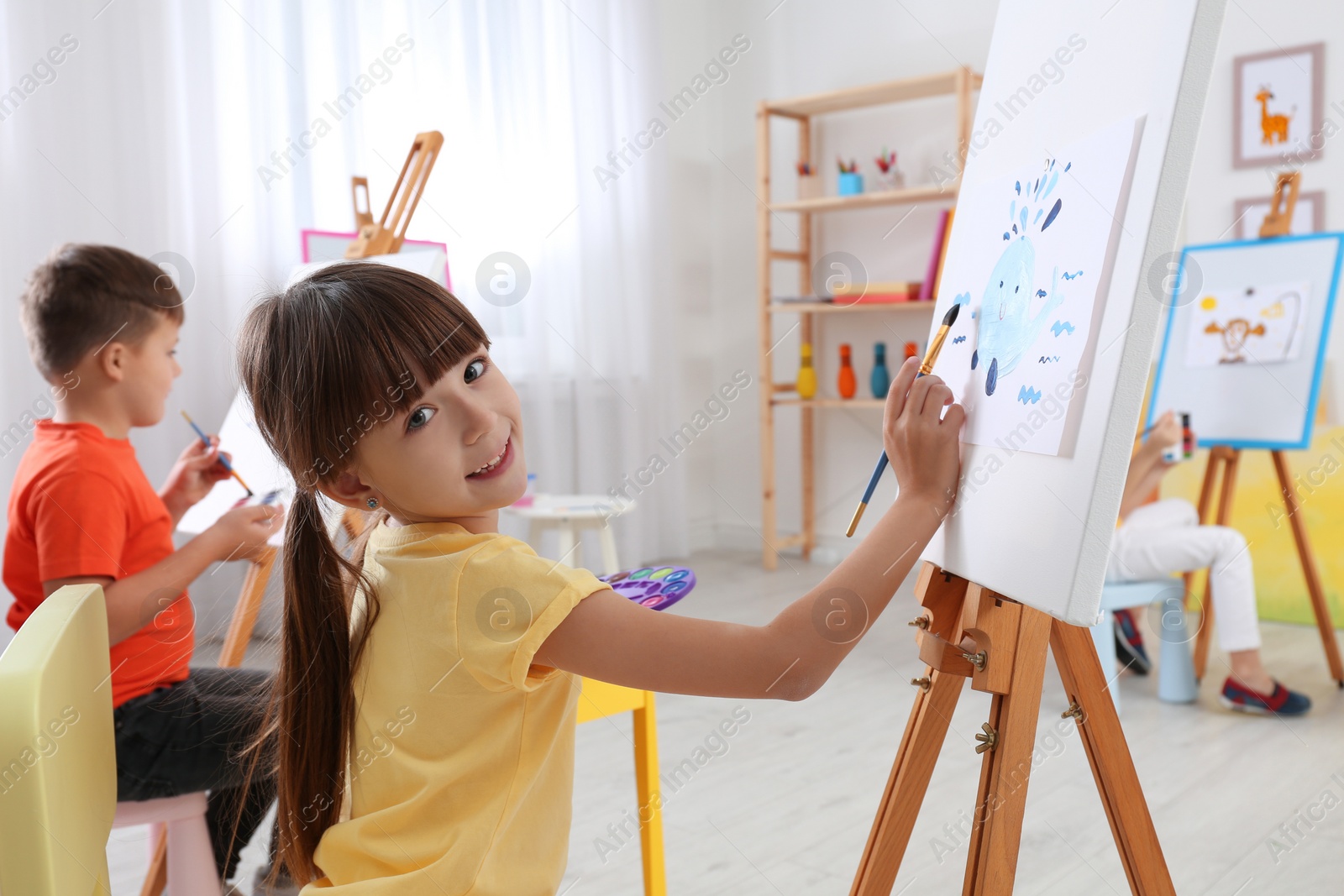 Photo of Cute little child painting during lesson in room